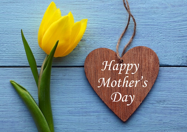 Szczęśliwy dzień matki kartkę z życzeniami z kwiatem tulipana żółty i ozdobne serce na starym drewnianym stole