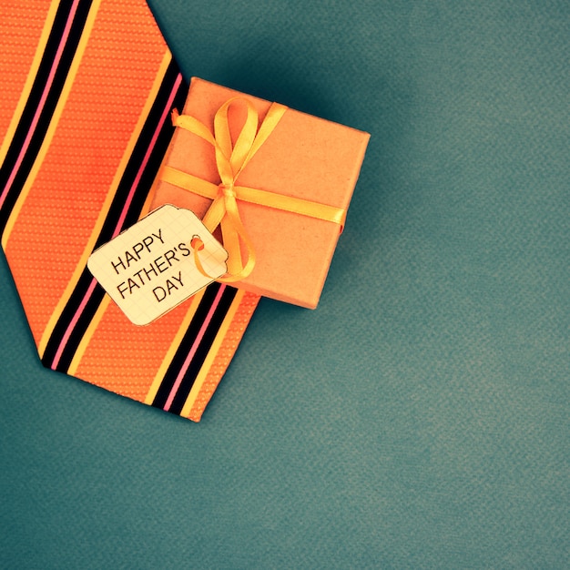 Szczęśliwy dzień ojca napis z krawatem i pudełko na niebieskim tle. Pozdrowienia i prezenty
