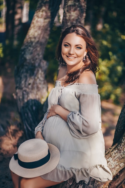 Szczęśliwy Elegancki Uśmiechnięty Kobieta W Ciąży Pozuje W Lesie