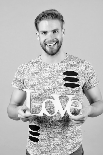 Szczęśliwy facet trzyma drewniany projekt słowa miłości