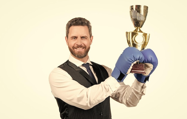 Szczęśliwy facet w rękawicach bokserskich i formalnej odzieży trzyma trofeum na białym tle sukces w biznesie