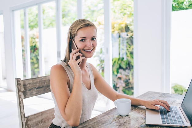 Szczęśliwy freelancer rozmawia przez telefon podczas korzystania z laptopa