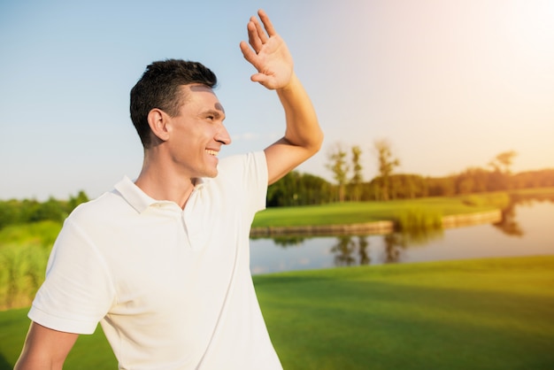 Szczęśliwy golfista w białej odzieży na słońcu.