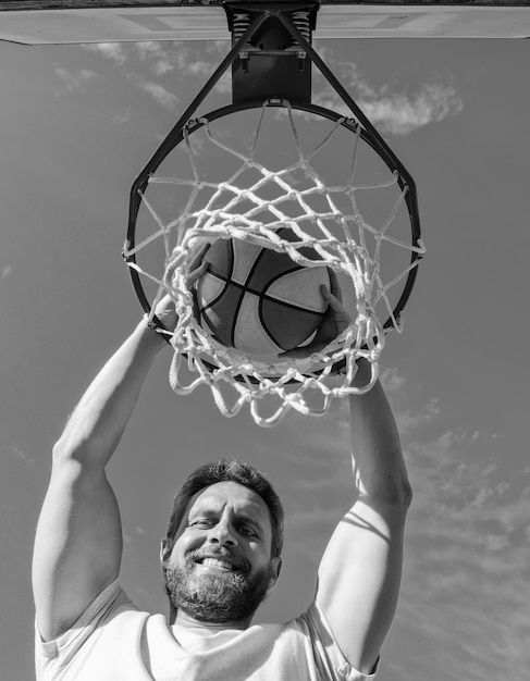 Szczęśliwy gracz rzuca piłkę do koszykówki przez wygrywanie kosza