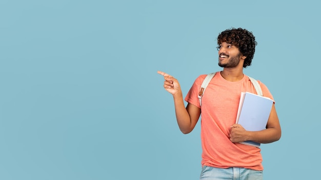 Szczęśliwy hinduski hipster, który idzie na studia, wskazując na bok