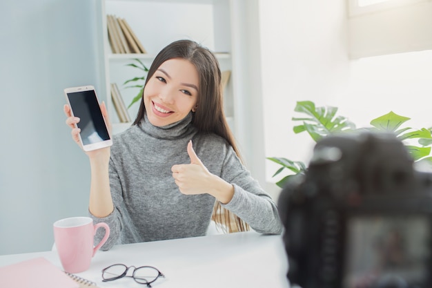 Szczęśliwy i fajny bloger pokazuje telefon do kamery vlogowej