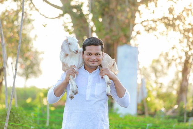 Szczęśliwy indyjski rolnik trzymający indyjską kozę