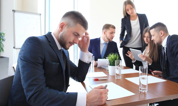 Szczęśliwy inteligentny biznesmen z kolegami z zespołu dyskutujących w tle