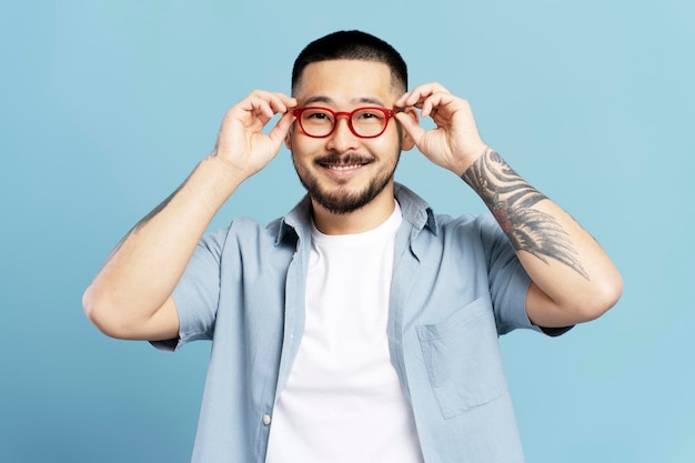 Szczęśliwy koreański hipster w czerwonych okularach patrzący na kamerę Koncepcja wizji