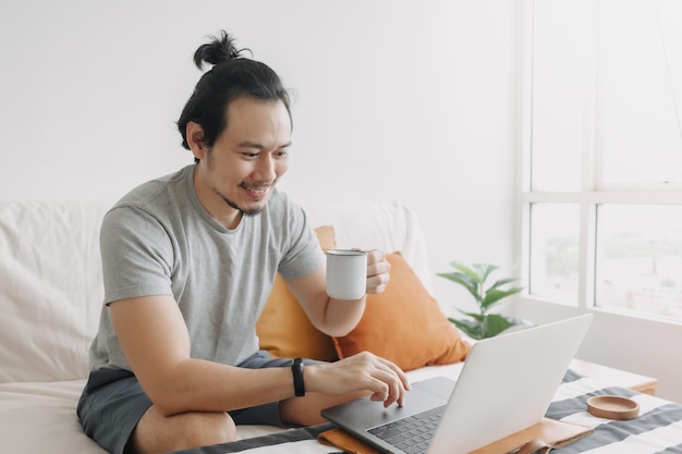 Szczęśliwy kreatywny mężczyzna pracuje na laptopie w swoim mieszkaniu w biurze domowym