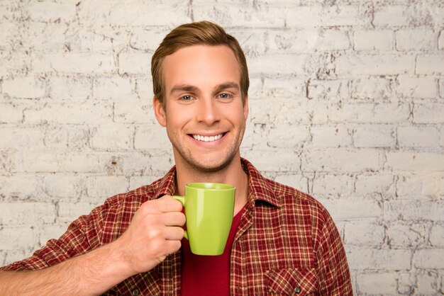 Zdjęcie szczęśliwy ładny mężczyzna trzyma kubek gorącej kawy