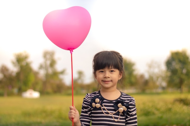 Zdjęcie szczęśliwy mały azjatykci dziewczyny mienia menchii balon w ręce