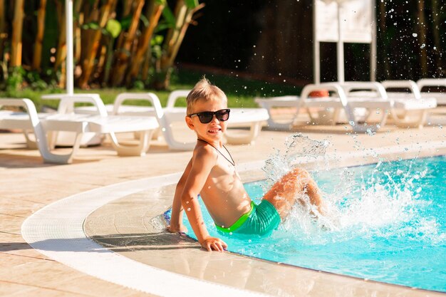 Zdjęcie szczęśliwy mały chłopiec bawi się na basenie w ośrodku