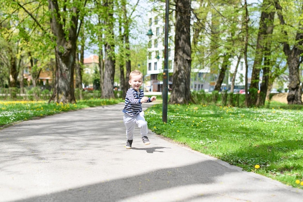 Szczęśliwy mały chłopiec bawiący się w parku