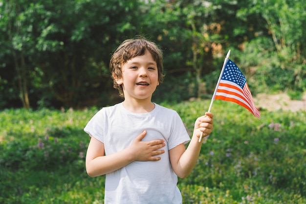 Szczęśliwy mały chłopiec patriotyczny trzymający amerykańską flagę USA świętuje 4 lipca Szczęśliwy dzień niepodległości
