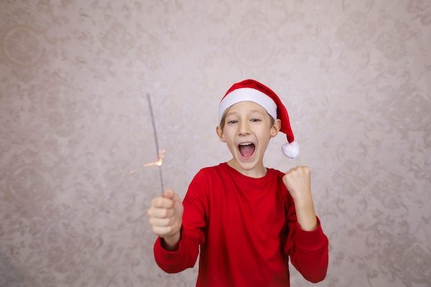 Zdjęcie szczęśliwy mały chłopiec w santa hat i trzymając brylant, sylwester