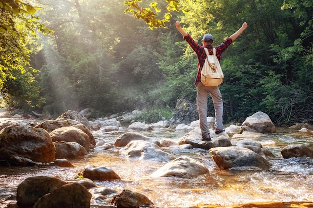 Szczęśliwy męski turysta trekking na świeżym powietrzu w lesie w pobliżu rzeki