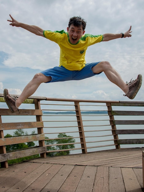 Zdjęcie szczęśliwy mężczyzna krzyczy, skacząc na promenadzie.