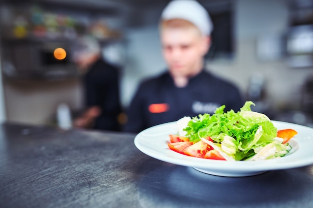 Szczęśliwy mężczyzna szef kuchni gotuje jedzenie w kuchni restauracji