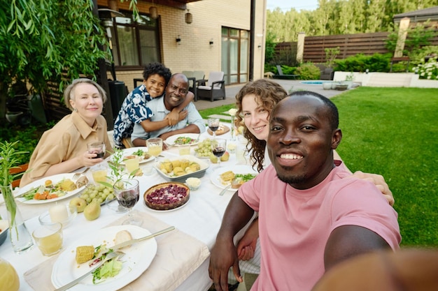 Zdjęcie szczęśliwy młody afroamerykanin robi selfie z dużą rodziną składającą się z żony, uroczego syna i dwóch dojrzałych rodziców