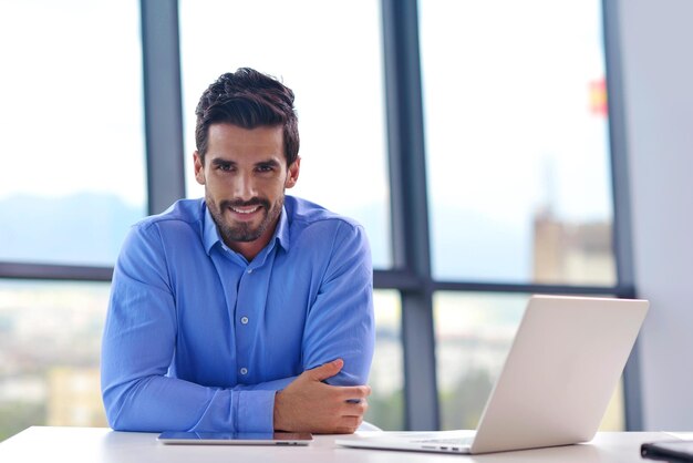 szczęśliwy młody człowiek biznesu pracuje w nowoczesnym biurze na komputerze