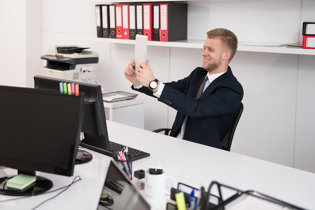 Zdjęcie szczęśliwy młody człowiek biznesu pracuje w nowoczesnym biurze na komputerze