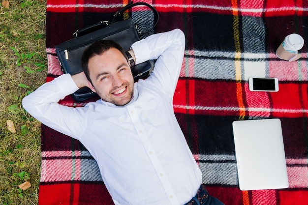 Zdjęcie szczęśliwy młody człowiek relaksuje na trawie z laptopem, widok od wierzchołka