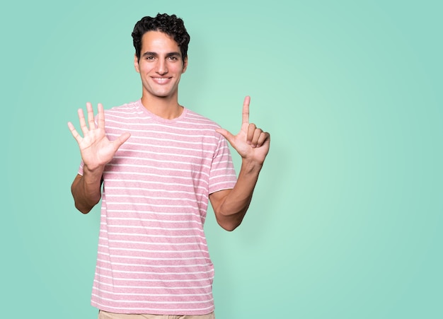 Szczęśliwy młody człowiek robi gestem numer siedem rękoma