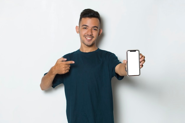 Szczęśliwy młody człowiek trzyma telefon komórkowy z pustym pustym ekranem na białym tle