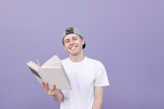 Szczęśliwy młody człowiek z książką na tle purpurowa ściana