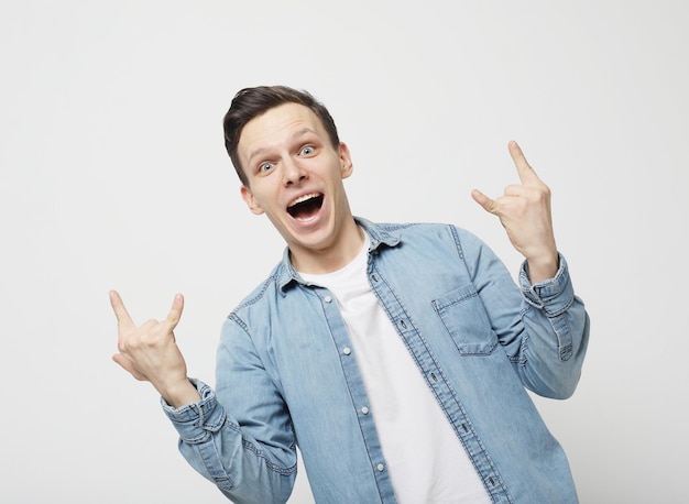 Szczęśliwy młody przystojny mężczyzna gestykuluje i trzyma usta