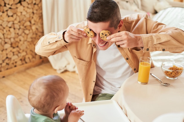 Szczęśliwy moment ojciec i syn jedzą śniadanie z ciastkami