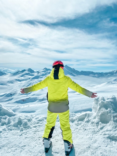 Szczęśliwy nastolatek w jasnym sportowym garniturze narciarskim w górach