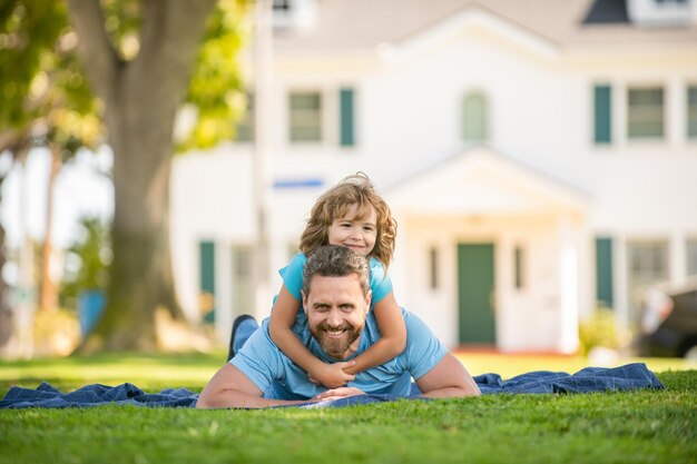 Szczęśliwy ojciec bawiący się z dzieckiem relaksuje się razem na zielonym parku trawiastych przyjaciół