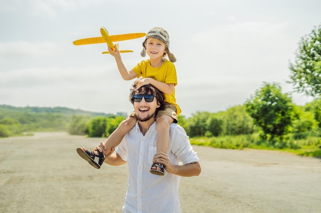 Szczęśliwy ojciec i syn bawiący się samolocikiem na tle starego pasa startowego Podróżowanie z koncepcją dzieci