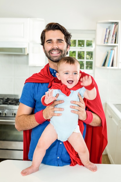 Szczęśliwy ojciec i syn w kostiumie superbohatera w domu