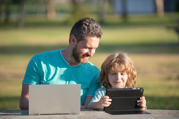 Szczęśliwy ojciec korzystający z laptopa relaksuje się z synem uczniakiem trzymającym laptopa baw się razem uśmiechnięty tata i l