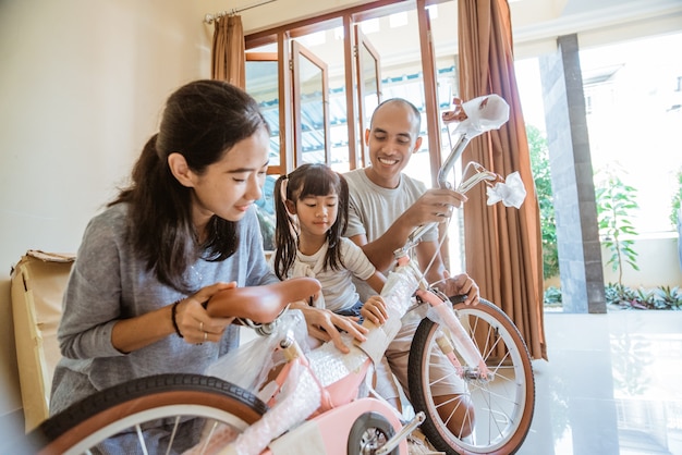 Szczęśliwy ojciec matka i córka wspólnie rozpakowują nowy mini rower