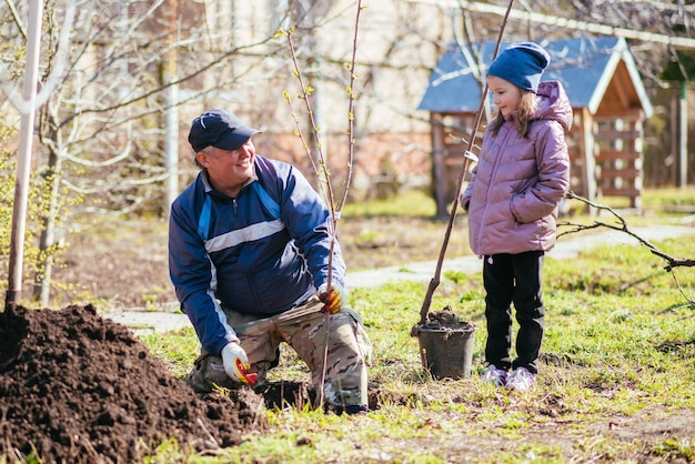 Szczęśliwy ojciec z córką sadzi drzewo owocowe