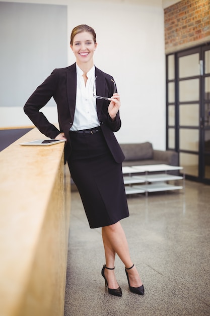 Szczęśliwy piękny bizneswoman opiera na kontuarze w biurze