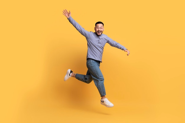 Szczęśliwy Podekscytowany Człowiek Azji Skoki W Powietrzu Na żółtym Tle