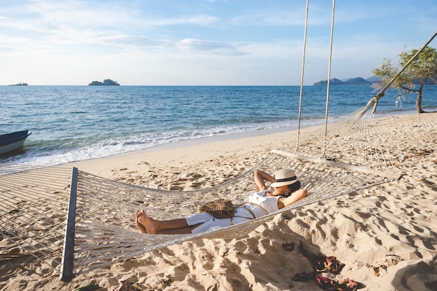 Szczęśliwy Podróżnik Azjatykcia Kobieta Z Kapeluszem Relaks W Hamaku Na Plaży W Koh Chang, Trad, Tajlandia