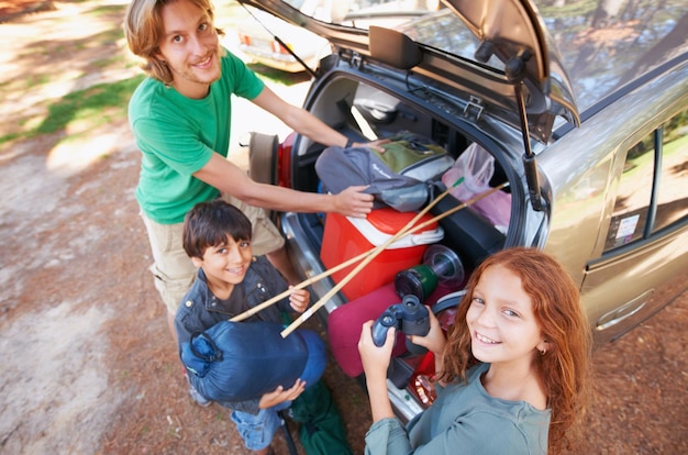 Zdjęcie szczęśliwy portret rodzinny i pakowanie samochodu na wakacje lub wakacje na kempingu razem w przyrodzie widok z góry ojca i dzieci z uśmiechem na weekend z przygodą na obozie letnim lub podróż w lesie