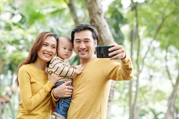 Szczęśliwy pozytywny Azjata biorąc selfie ze swoją ładną żoną i uroczym synkiem