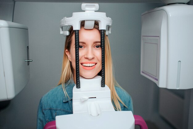 Zdjęcie szczęśliwy pozytywny młodej kobiety obsiadanie w dentysty pokoju