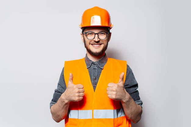 Szczęśliwy pracownik budowlany pokazując kciuk do góry na białym tle