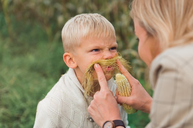 Szczęśliwy przedszkolak bawi się z mamą na świeżym powietrzu, bawiąc się na polu kukurydzy