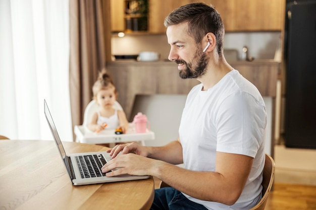 Szczęśliwy przypadkowy biznesmen siedzi w domu i pracuje na laptopie