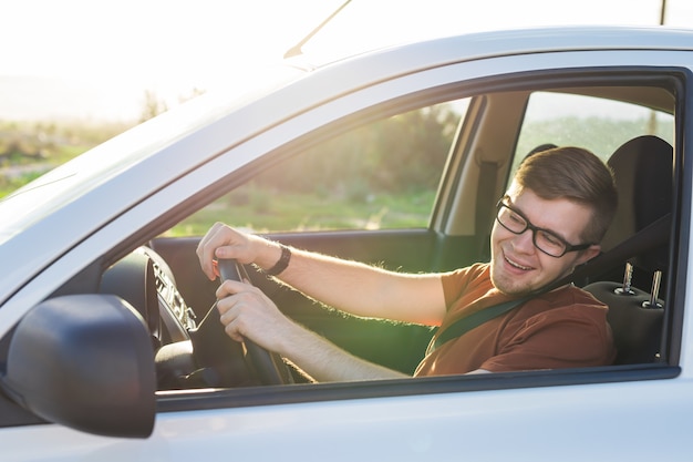 Szczęśliwy przystojny młody mężczyzna w brązowym T-shircie prowadzący samochód