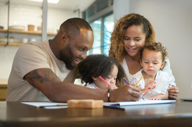 Szczęśliwy rodzic Afroamerykanów bawiący się i rysujący z córkami w domu
